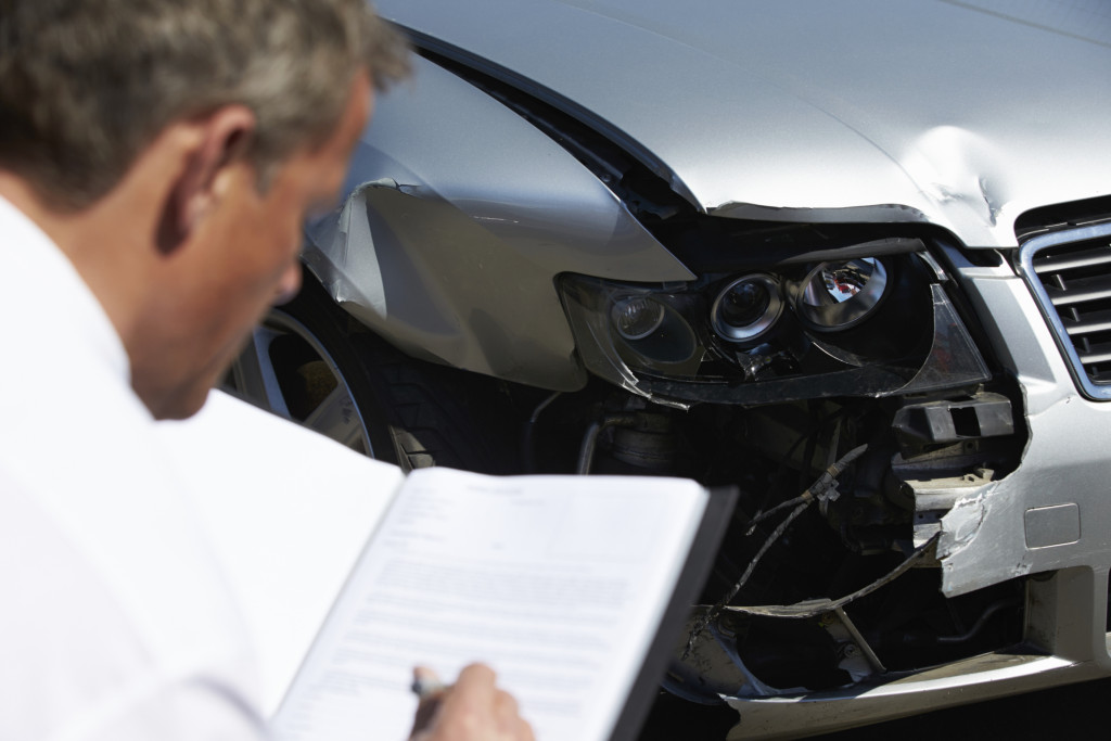 Illustration of an insurance claims adjuster examining a vehicle. (monkeybusinessimages/iStock/Thinkstock)